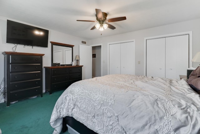 bedroom featuring ceiling fan, dark carpet, two closets, and visible vents