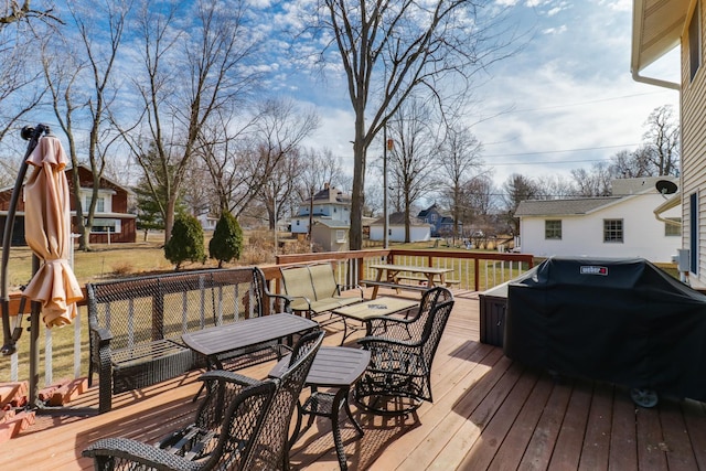 wooden deck featuring outdoor dining space, a grill, and a residential view