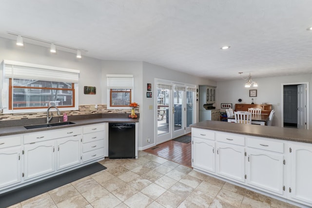 kitchen featuring dark countertops, black dishwasher, white cabinetry, and a sink