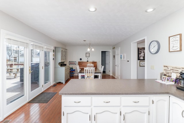 kitchen with a peninsula, light wood-style floors, white cabinetry, pendant lighting, and recessed lighting