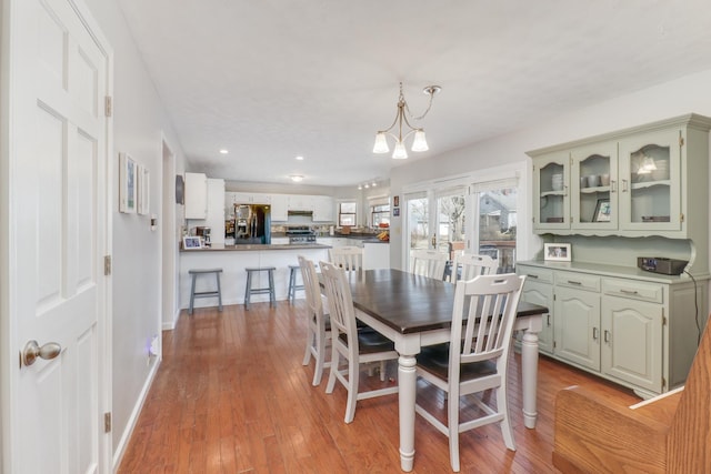 dining space with a notable chandelier, baseboards, and light wood-style floors