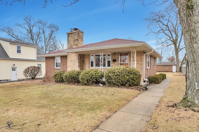 view of front of house with brick siding, a chimney, and a front lawn