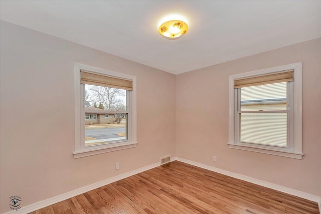 spare room featuring light wood-style floors, visible vents, and baseboards