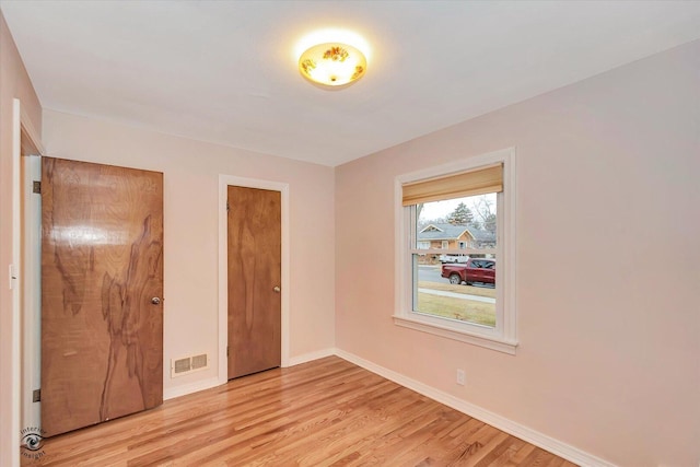 unfurnished bedroom with light wood finished floors, visible vents, and baseboards