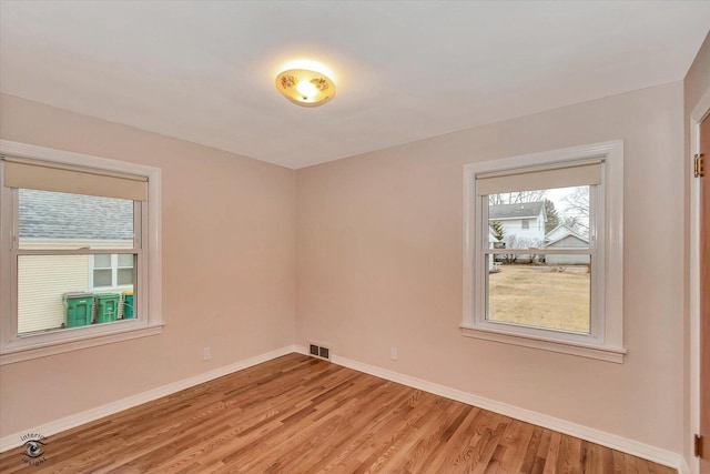 unfurnished room featuring light wood-style flooring, visible vents, and baseboards