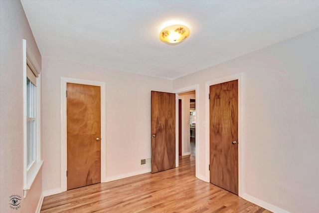 unfurnished bedroom with light wood-style floors, visible vents, and baseboards