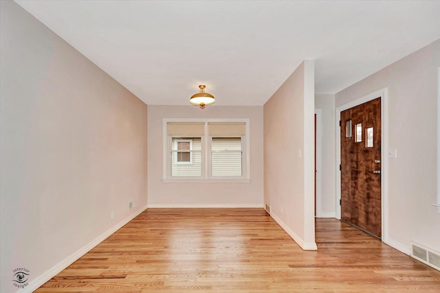 unfurnished room with baseboards, visible vents, and light wood finished floors