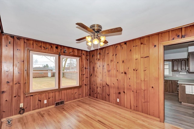 empty room with visible vents, ceiling fan, and wood finished floors