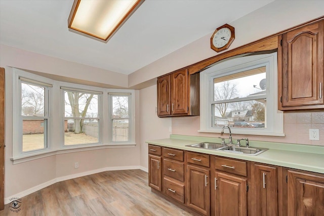 kitchen featuring light countertops, decorative backsplash, a sink, and light wood-style floors