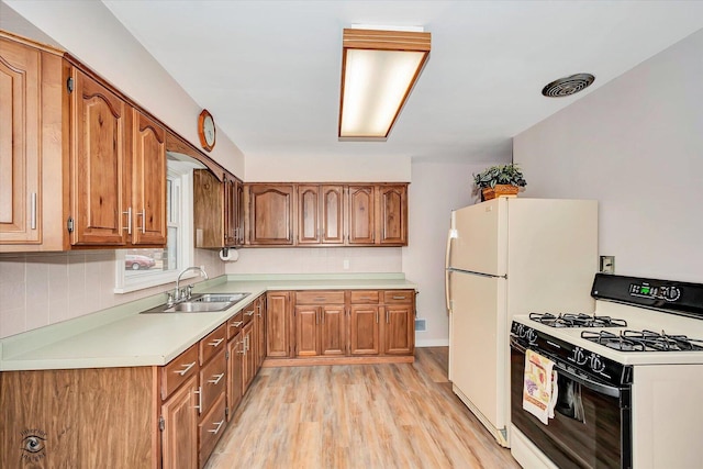 kitchen with brown cabinetry, range with gas cooktop, and a sink