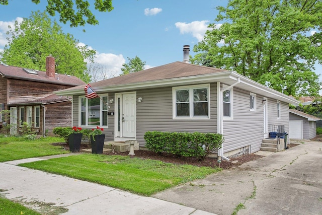 view of front of home with a front lawn, an outdoor structure, and a detached garage