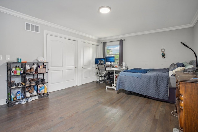 bedroom featuring multiple closets, visible vents, crown molding, and wood finished floors