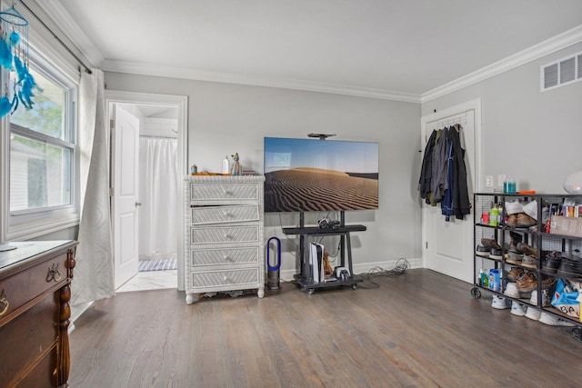 bedroom with ornamental molding, wood finished floors, visible vents, and baseboards