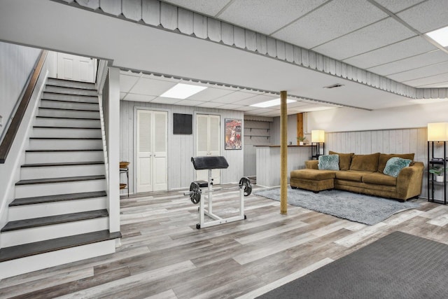 workout room with visible vents, wood finished floors, a paneled ceiling, and wooden walls