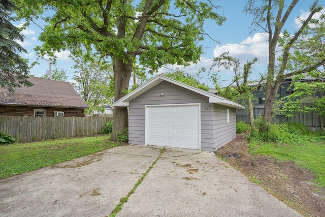 detached garage featuring driveway and fence