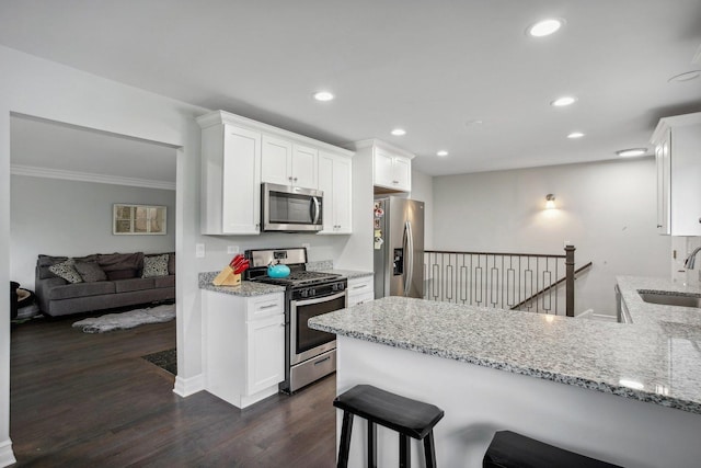 kitchen featuring stainless steel appliances, light stone counters, a sink, and white cabinets