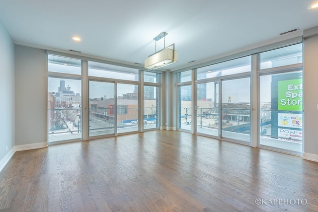 spare room featuring a view of city, visible vents, expansive windows, and wood finished floors