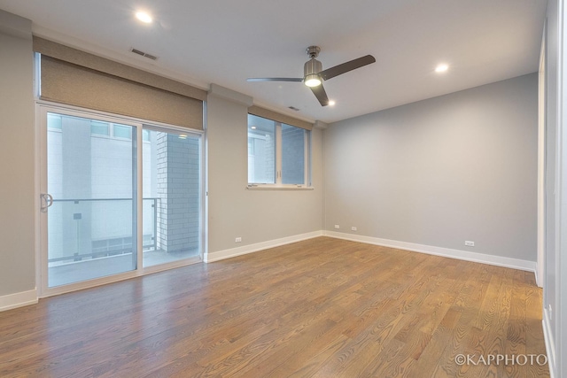 unfurnished room with wood finished floors, visible vents, and baseboards