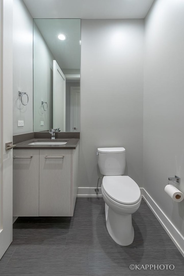 bathroom featuring toilet, baseboards, and vanity