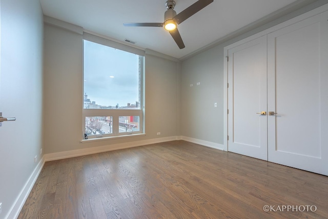 empty room with wood finished floors, visible vents, and baseboards