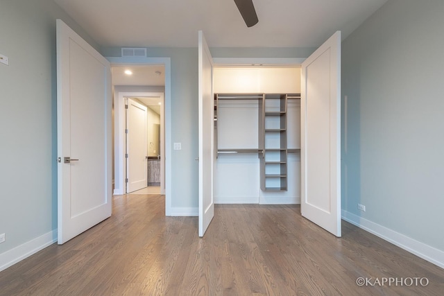 unfurnished bedroom with a closet, visible vents, baseboards, and wood finished floors