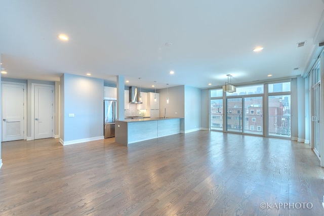 unfurnished living room with recessed lighting, wood finished floors, visible vents, and baseboards