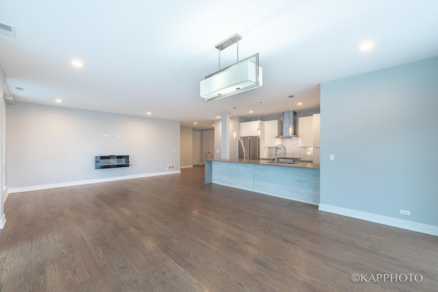 unfurnished living room featuring dark wood-style floors, a glass covered fireplace, a sink, and baseboards