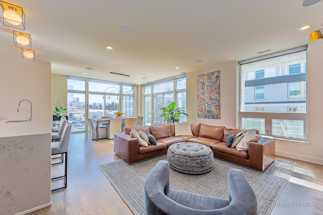 living area with baseboards, wood finished floors, a view of city, a wall of windows, and recessed lighting