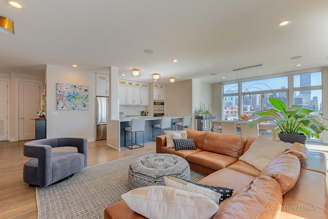 living area featuring light wood-style floors, a view of city, baseboards, and recessed lighting