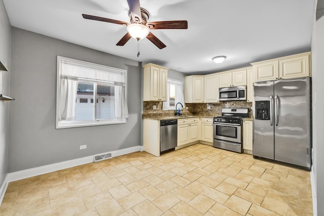 kitchen featuring stainless steel appliances, cream cabinets, a sink, and visible vents