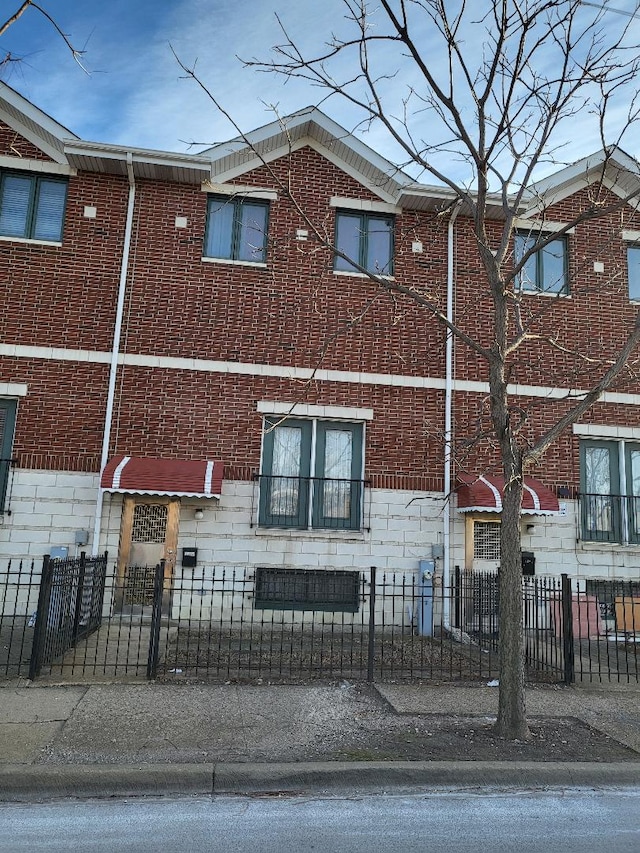 townhome / multi-family property featuring brick siding and a fenced front yard