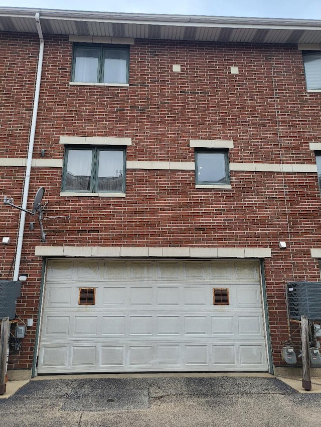 exterior space featuring a garage, brick siding, and driveway