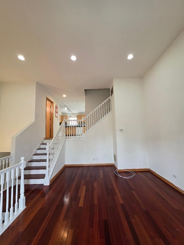 unfurnished room featuring dark wood-style floors, recessed lighting, baseboards, and stairs