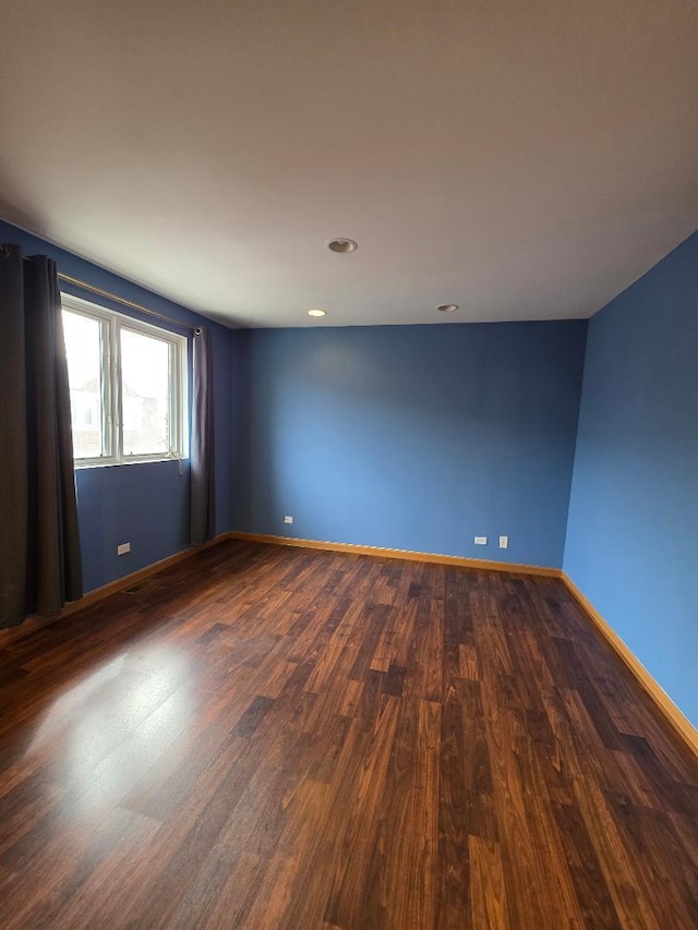 spare room with baseboards and dark wood finished floors