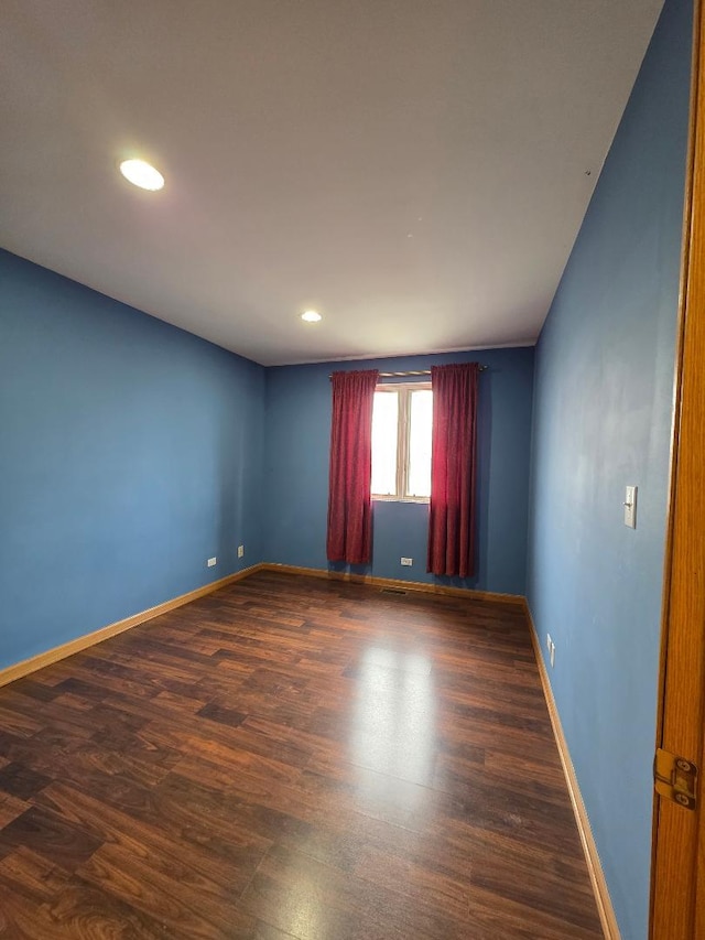 spare room featuring baseboards, dark wood-type flooring, and recessed lighting