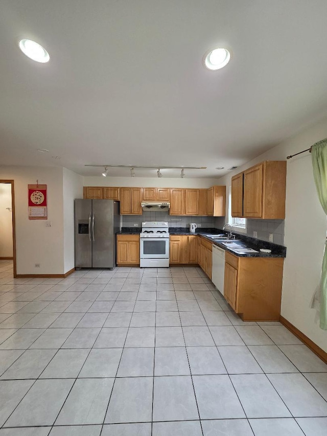 kitchen featuring light tile patterned floors, white appliances, backsplash, brown cabinetry, and dark countertops