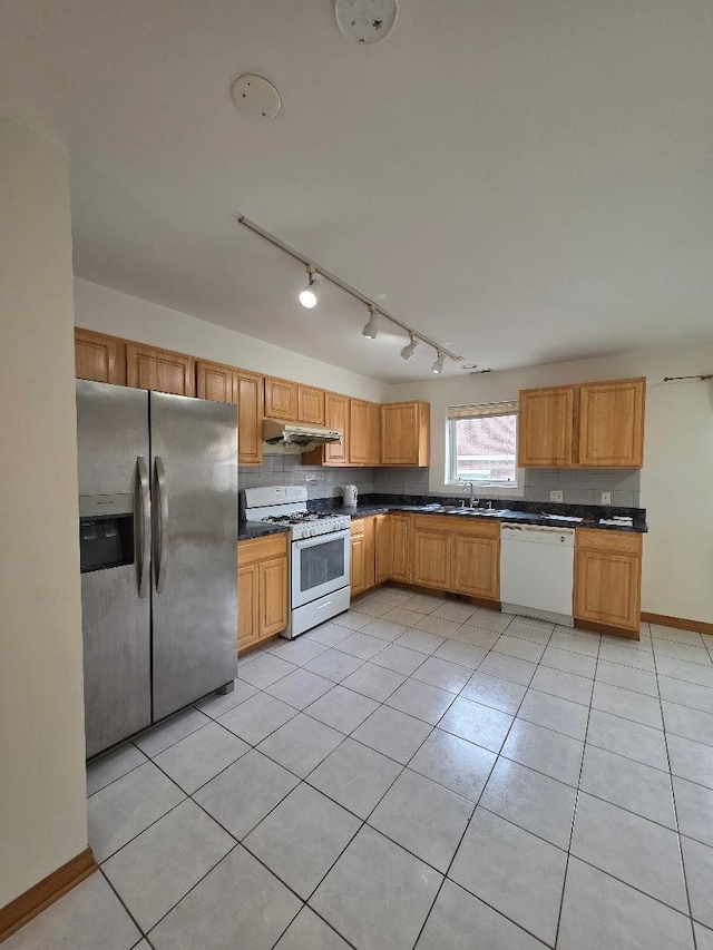 kitchen with dark countertops, white appliances, tasteful backsplash, and under cabinet range hood