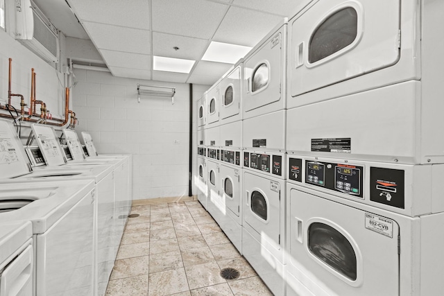 community laundry room featuring stacked washer / dryer, washer and clothes dryer, and concrete block wall