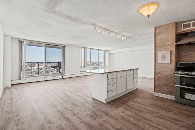 kitchen featuring light wood-type flooring, gas range, white cabinetry, and light countertops