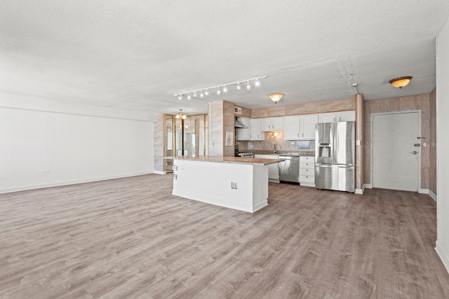 kitchen featuring appliances with stainless steel finishes, open floor plan, white cabinetry, a kitchen island, and light wood-type flooring