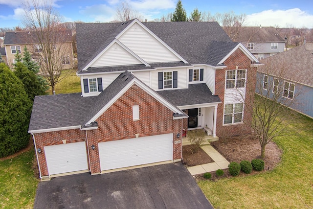 traditional-style house featuring aphalt driveway, a garage, a shingled roof, brick siding, and a front lawn