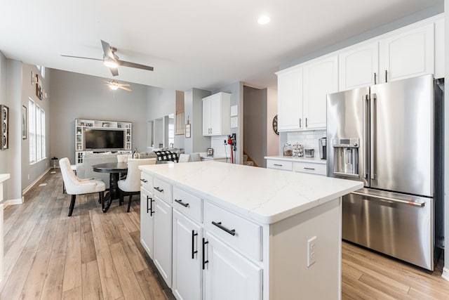 kitchen featuring a kitchen island, white cabinetry, high end fridge, light wood finished floors, and tasteful backsplash