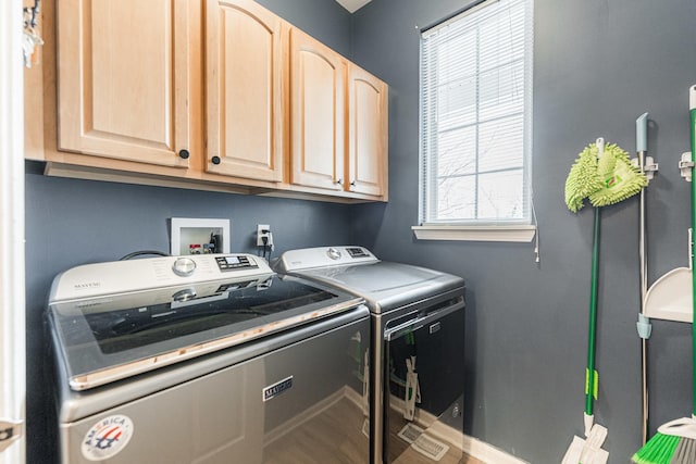 washroom featuring cabinet space, baseboards, and separate washer and dryer