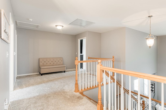 corridor featuring attic access, baseboards, carpet flooring, and an upstairs landing