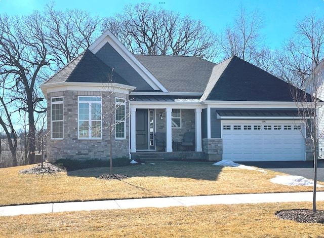 view of front of property with aphalt driveway, a shingled roof, an attached garage, a front yard, and stone siding