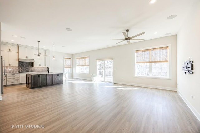 unfurnished living room with light wood finished floors, recessed lighting, and baseboards