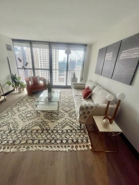 living area featuring visible vents, a wall of windows, and wood finished floors