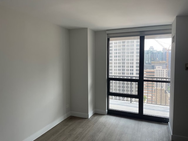 unfurnished room with a view of city, plenty of natural light, and baseboards