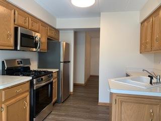 kitchen featuring a sink, brown cabinetry, stainless steel appliances, and light countertops