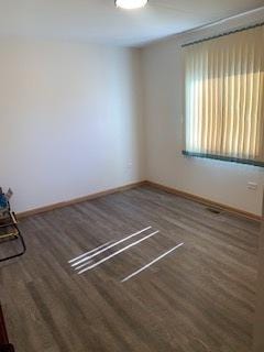 empty room with dark wood-style floors and baseboards